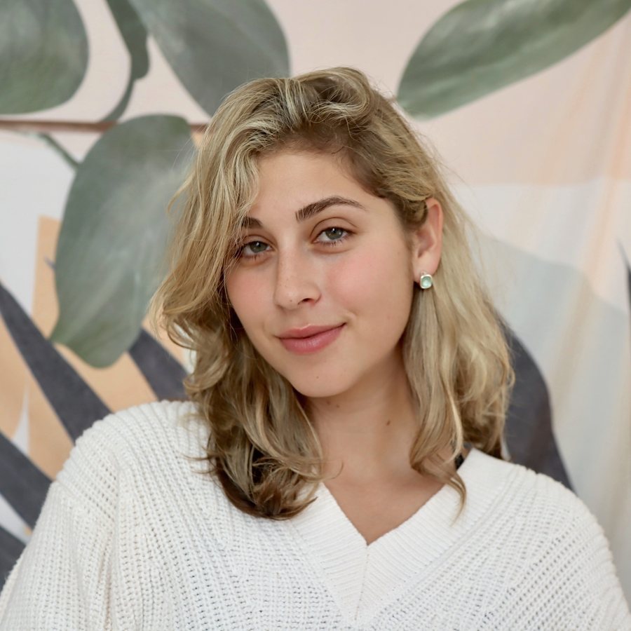 Portrait of Alexa Bush smiling, in a white knit sweater